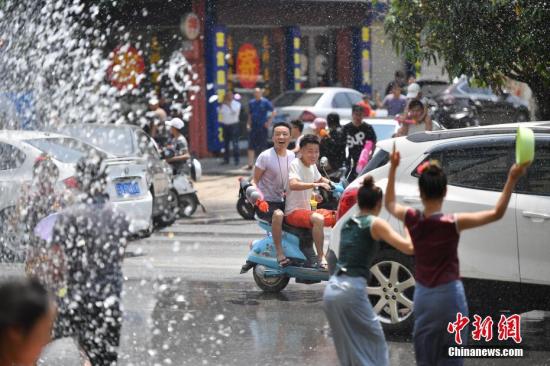 资料图：在云南省德宏傣族景颇族自治州瑞丽市，泼水节期间，民众相约走上街头泼水狂欢。 a 