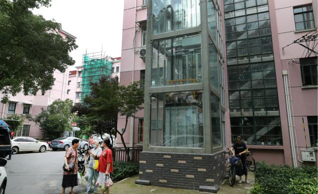 在上海市长宁区北新泾街道新泾六村，居民在加装了电梯的12号楼旁聊天(2020年6月23日摄)。新华社图。