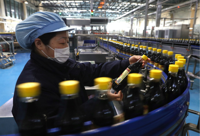 2月18日，在江苏省镇江市，工人在一家食醋酿造企业的灌装生产线上检查产品。新华社图。